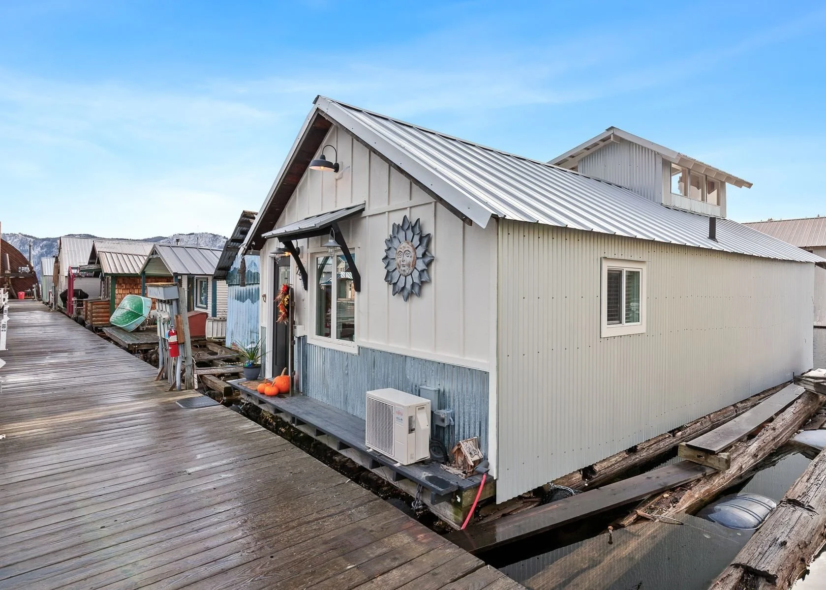 Floating house on a wooden dock with a mountain view in the background.
