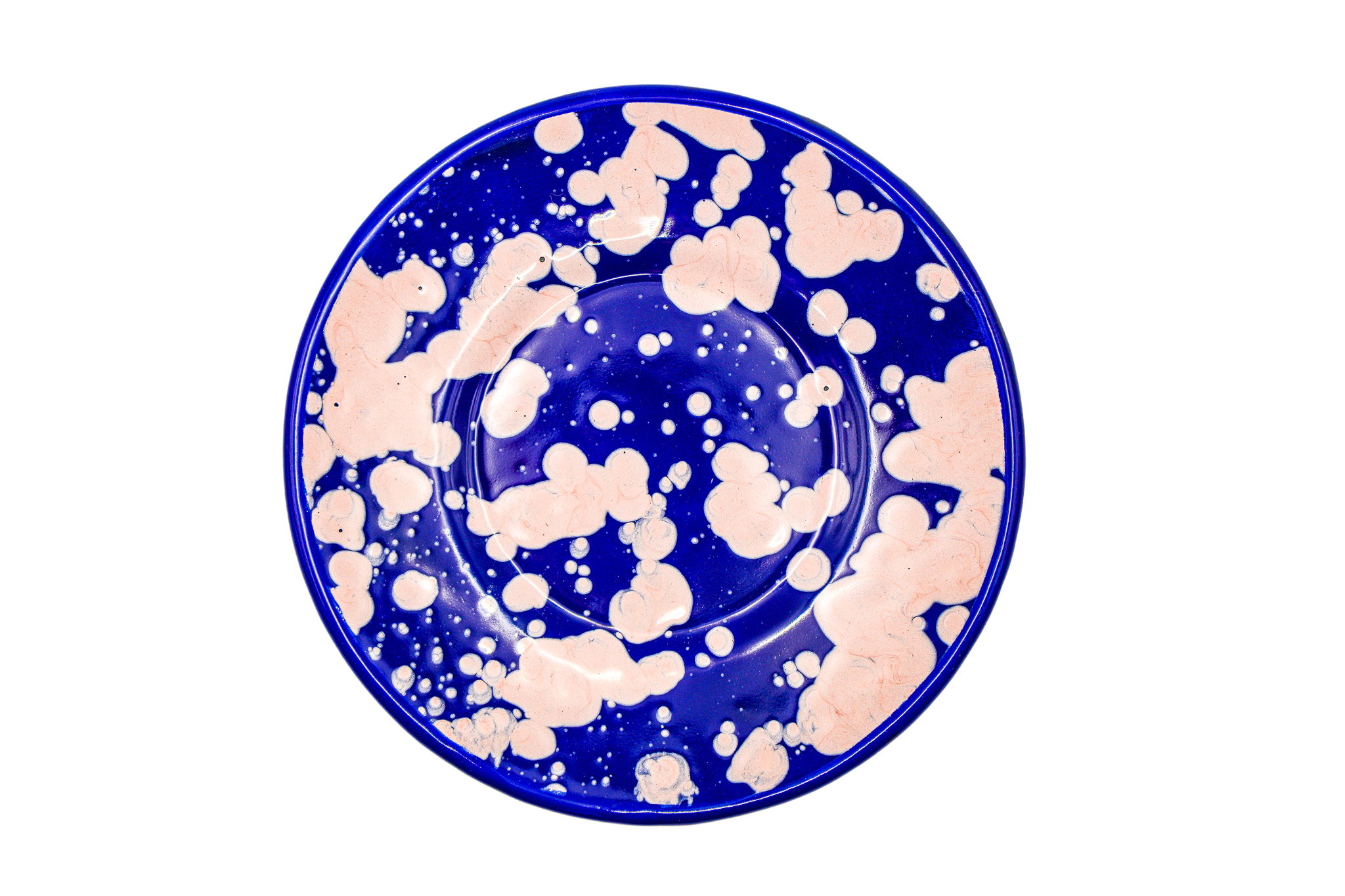 A blue plate with pinkish-white paint splatters.