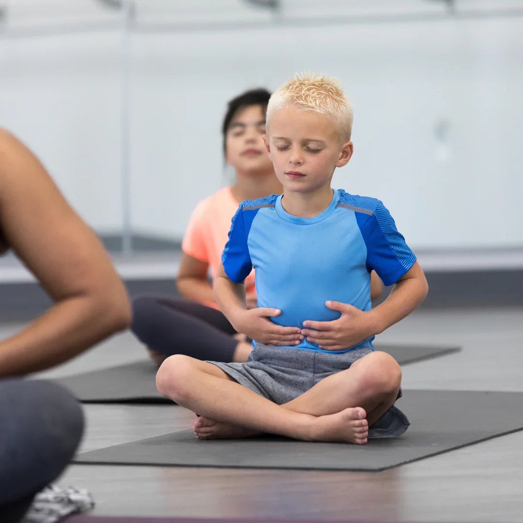 A boy using diaphragmatic breathing to help calm and center himself in a classroom gym environment