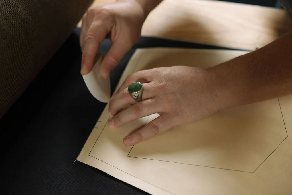 A person is measuring and marking a piece of paper with a corner template, using their right hand for holding and their left hand for tracing.