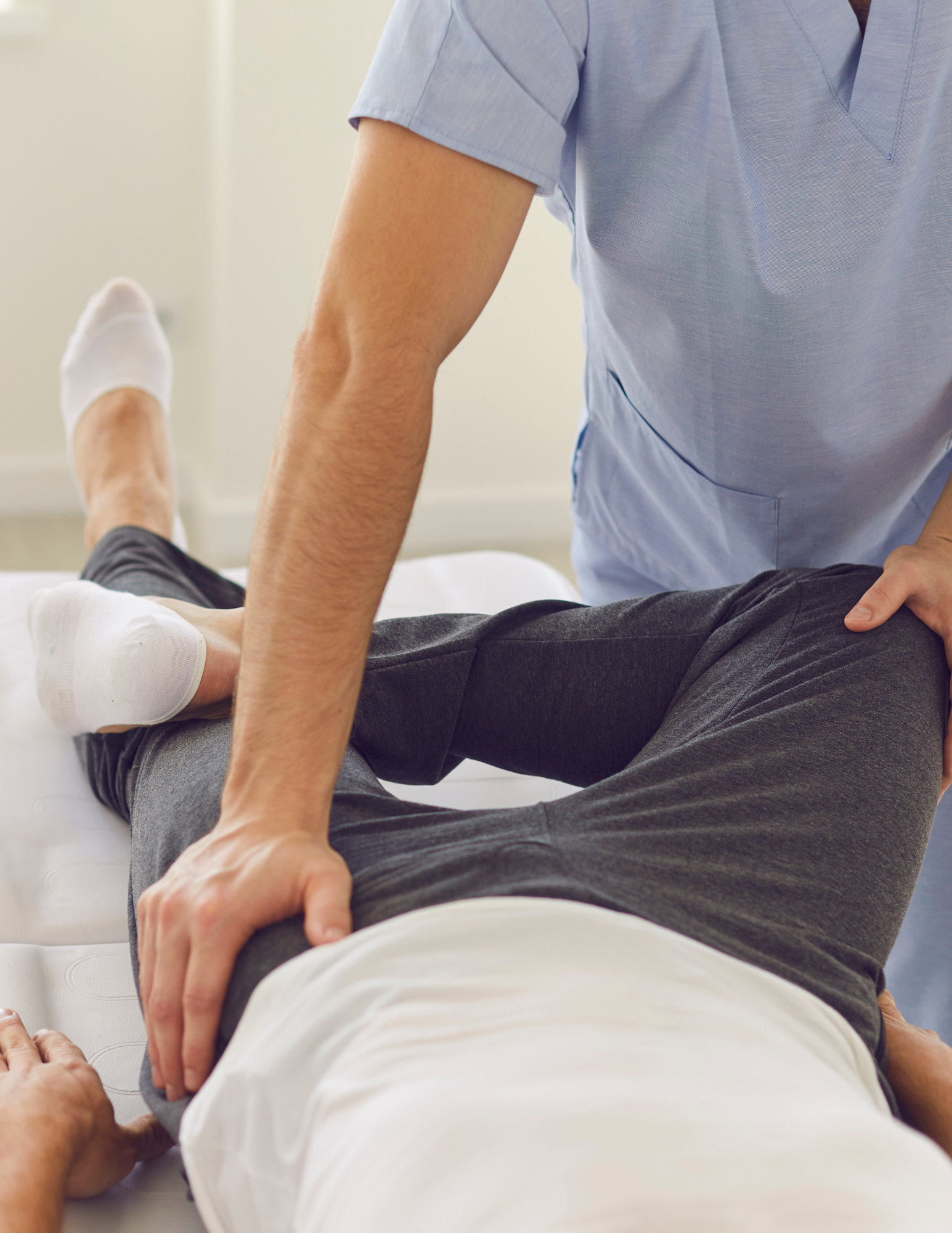Physical therapist performing rehabilitation exercises on a patient lying on a treatment table.