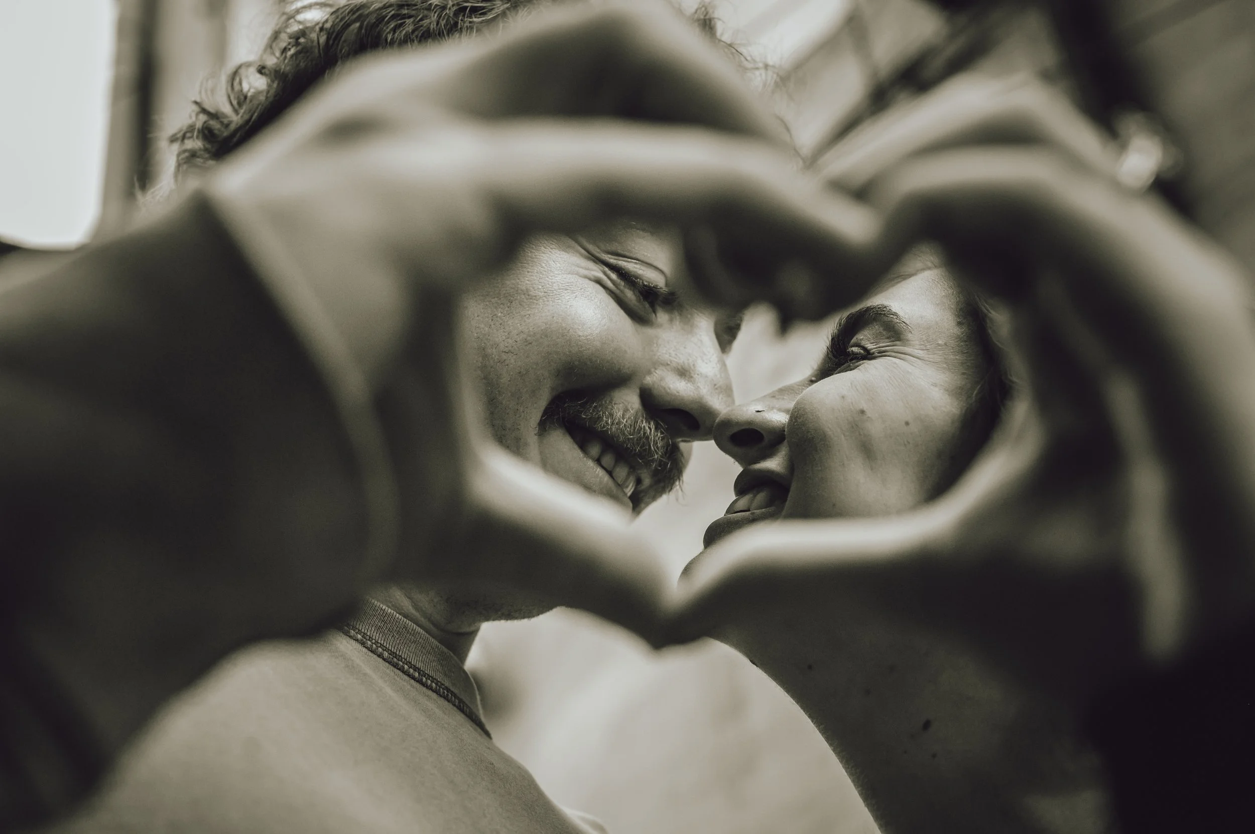 Newburgh engaged couple touching noses creating a heart shape with their hands together showing love