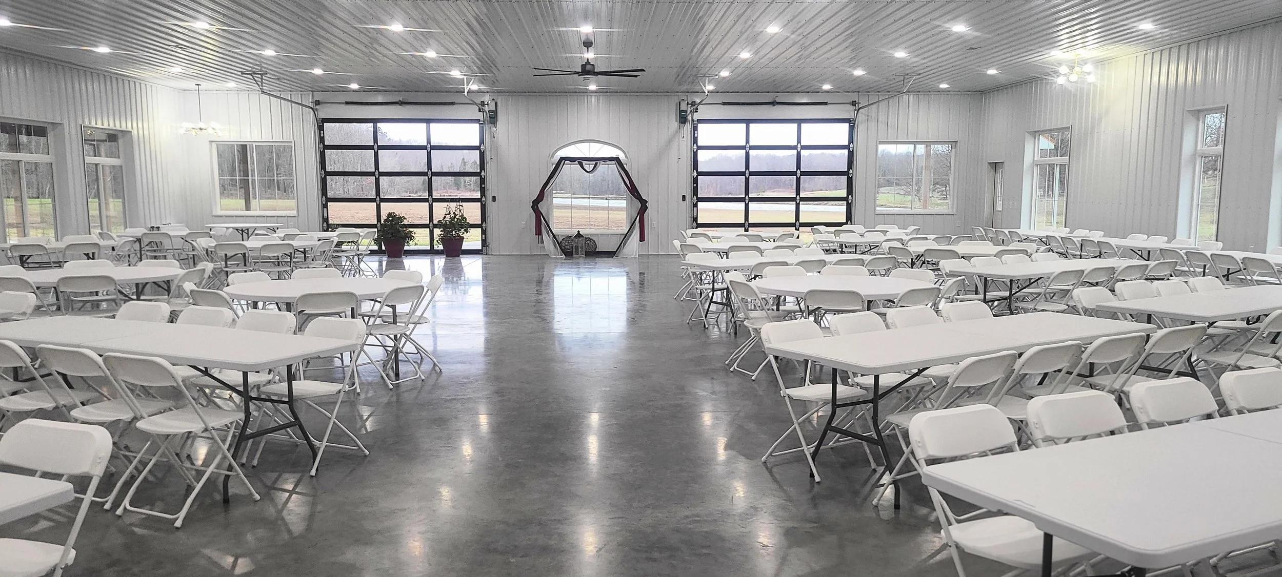 Climate controlled wedding venue space Kentucky Owensboro White tables and chairs for winter event warm cozy complete 360 views from within warm space