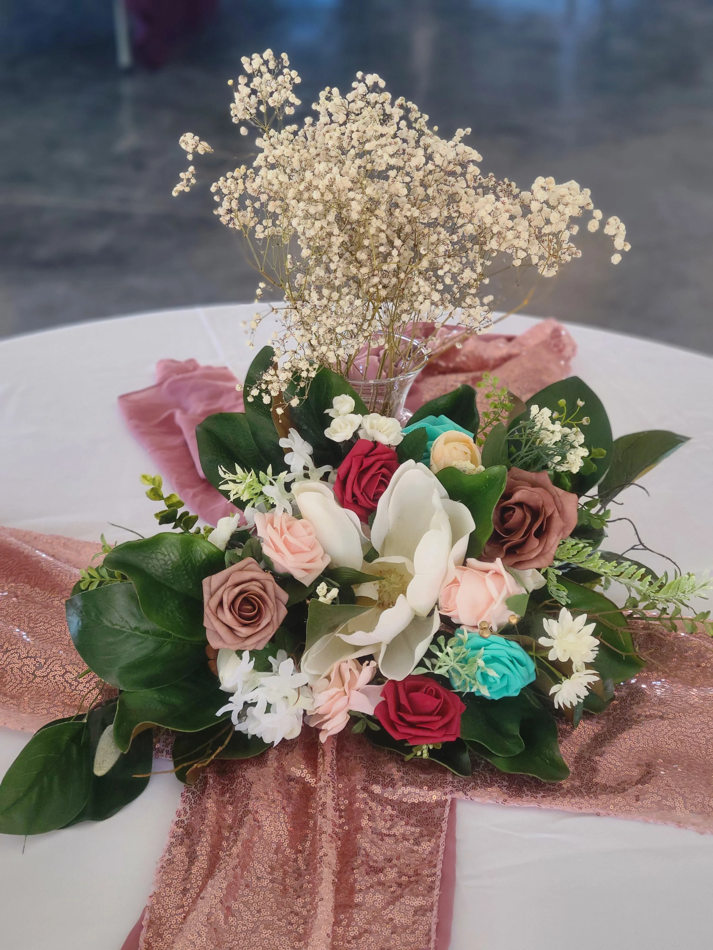 Floral centerpiece magnolia leaf babys breath rose gold table runners white table cloth burgundy roses white roses teal blue roses foam flowers magnolia bloom in center Kentucky Indiana Tennessee wedding venue decor
