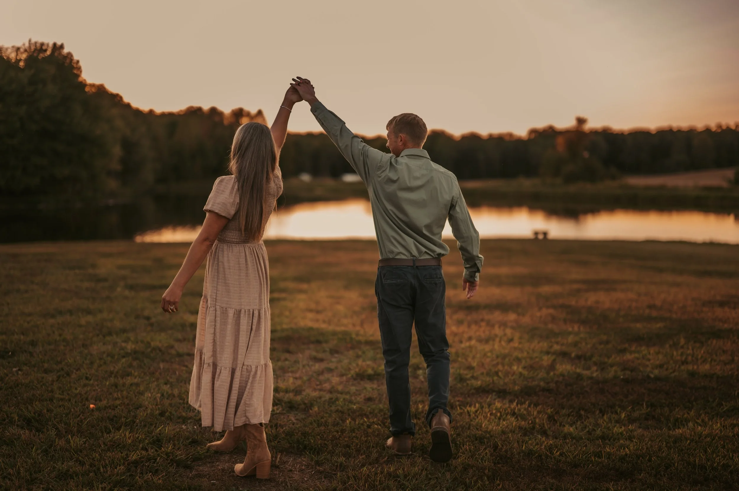 Engaged couple at Utica Kentucky wedding venue engagement photos lake side tan dress green shirt holding hands celebrating engagement planning wedding details mature trees shadows lake water
