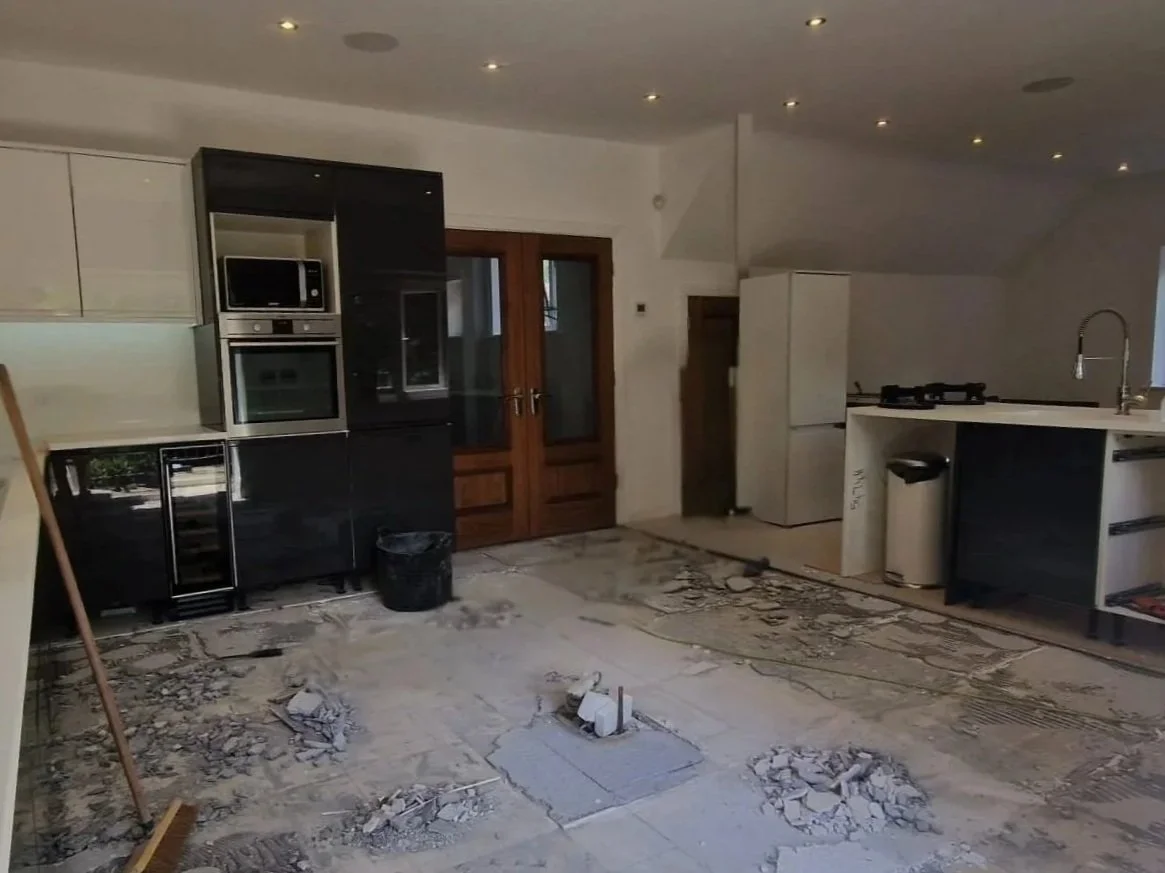 Kitchen with some construction or renovation work ongoing, debris on the floor, double door, refrigerator, and sink visible.