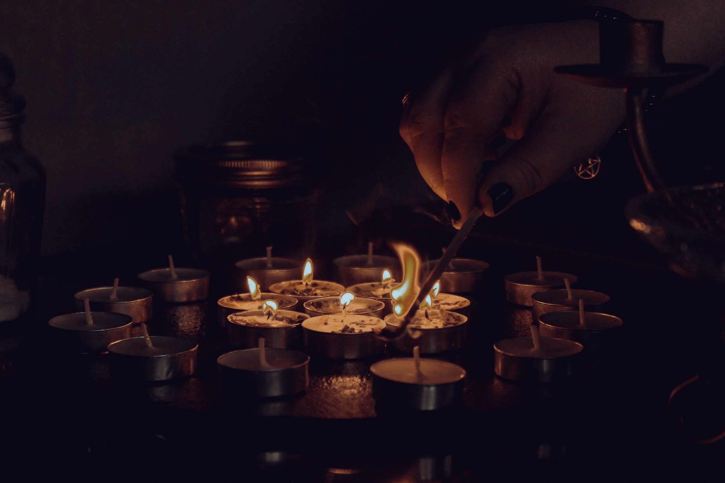 abundance candles being lit by a hand wearing a pentacle on her wrist, abundance prosperity and success in business ritual candle circle