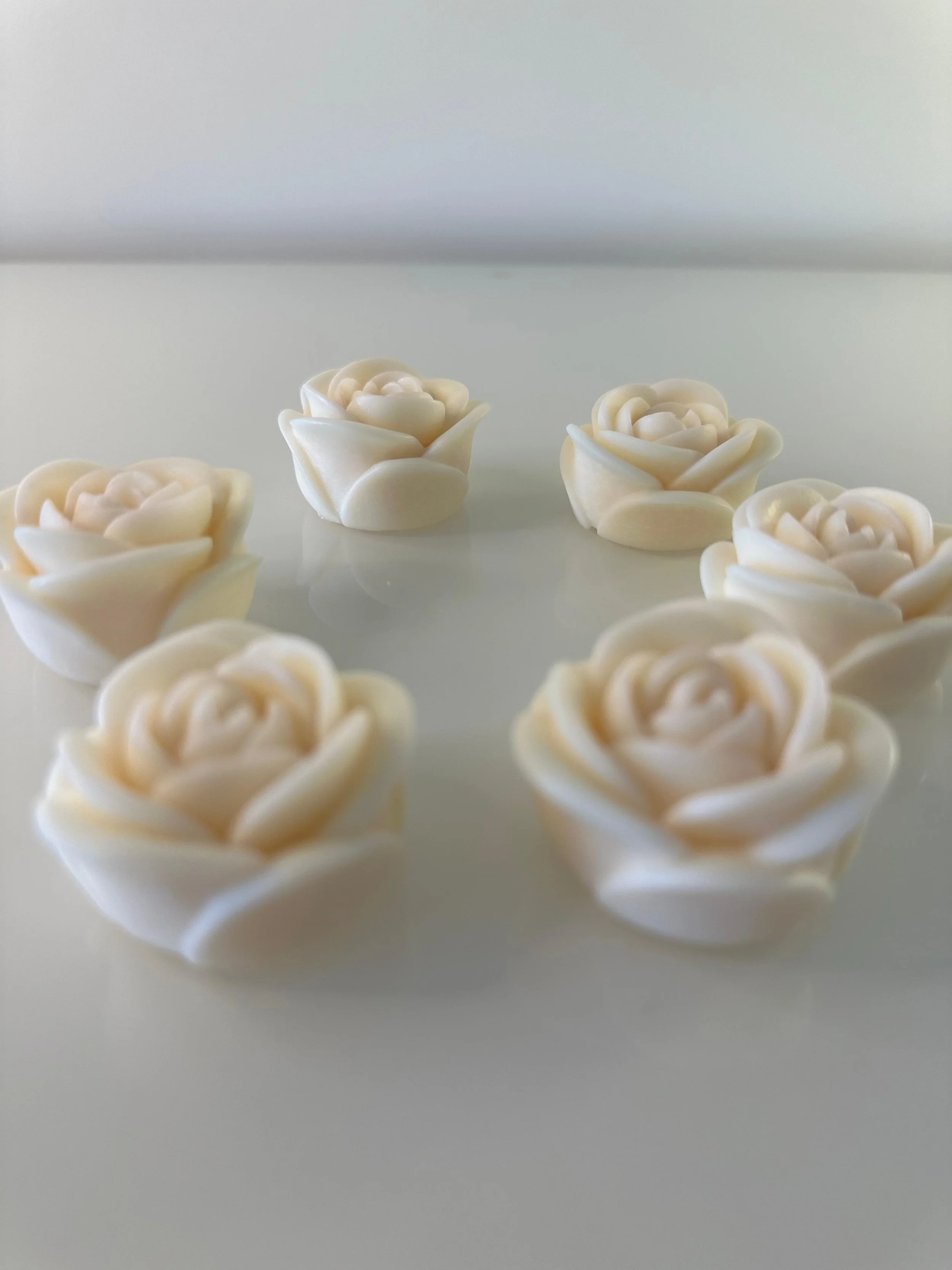 Cream-colored floral-shaped candies arranged in a circle on a white surface.