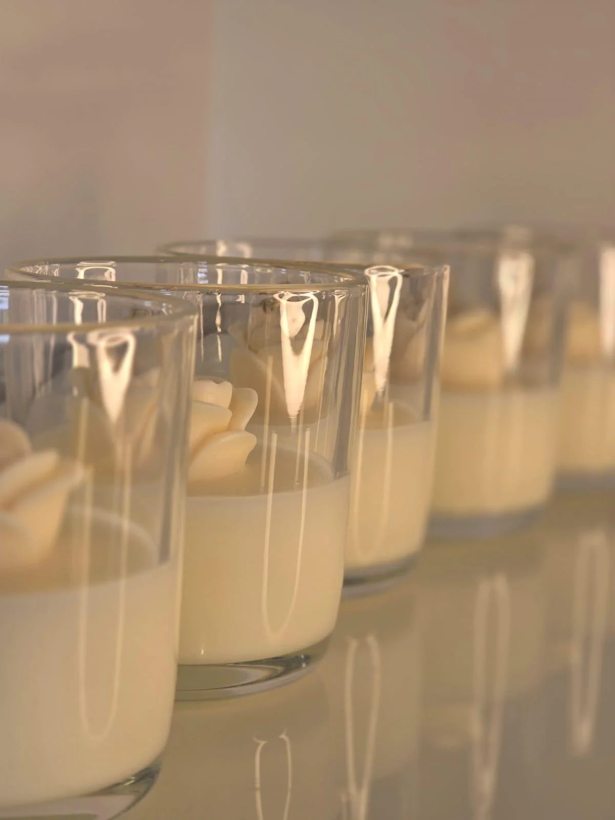 Close-up of several lit white candles in clear glass holders, arranged in a row.