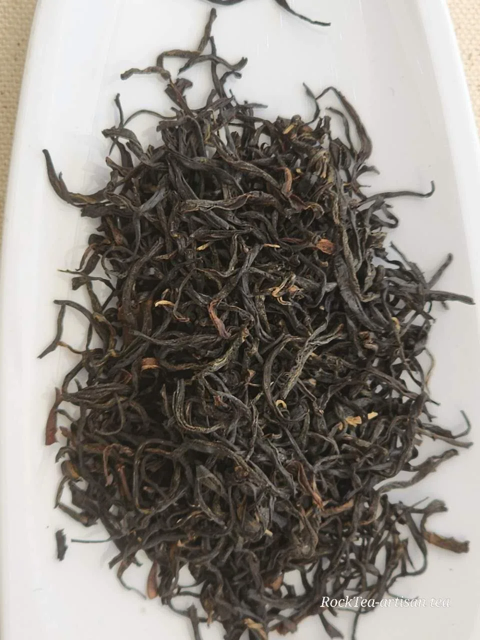 Wuyi Mountain Lapsang Souchong loose leaf black tea, traditional smoky artisan processing, twisted dark leaves.