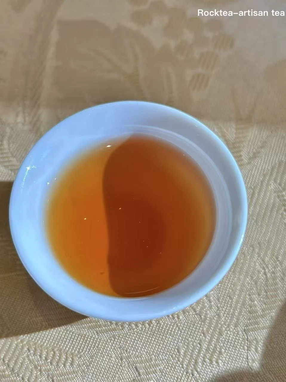 A cup of brewed  black tea displaying a deep amber-red color and rich lychee aroma.