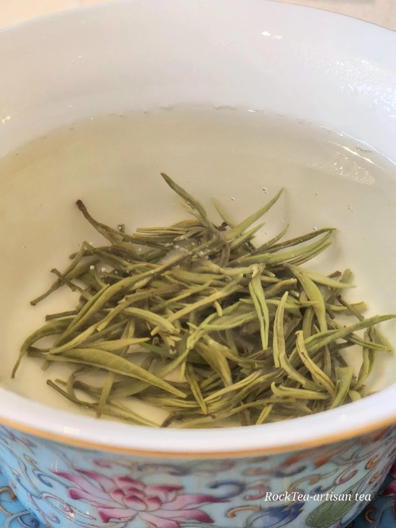 A clear cup of freshly brewed Guzhang Maojian green tea, with a floral aroma and bright, light yellow tea liquor.Naturally sweet and rich in Selenium.
