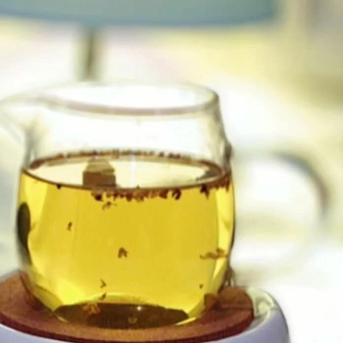 Clear-yellow infusion of Grade 1 Golden Osmanthus tea in a glass pitcher, releasing a rich and natural honey-sweet aroma.