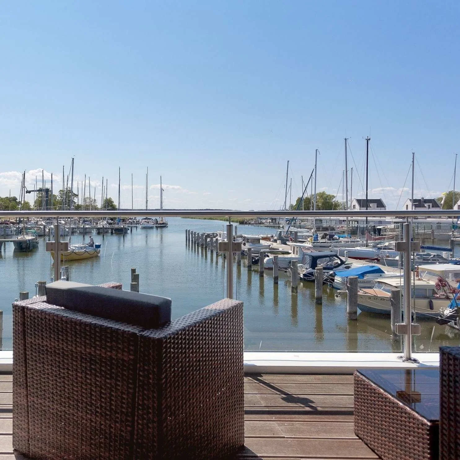 Terrasse des Floating House Yachthafen Perle mit Rattansesseln und direktem Blick auf den Yachthafen Peenemünde
