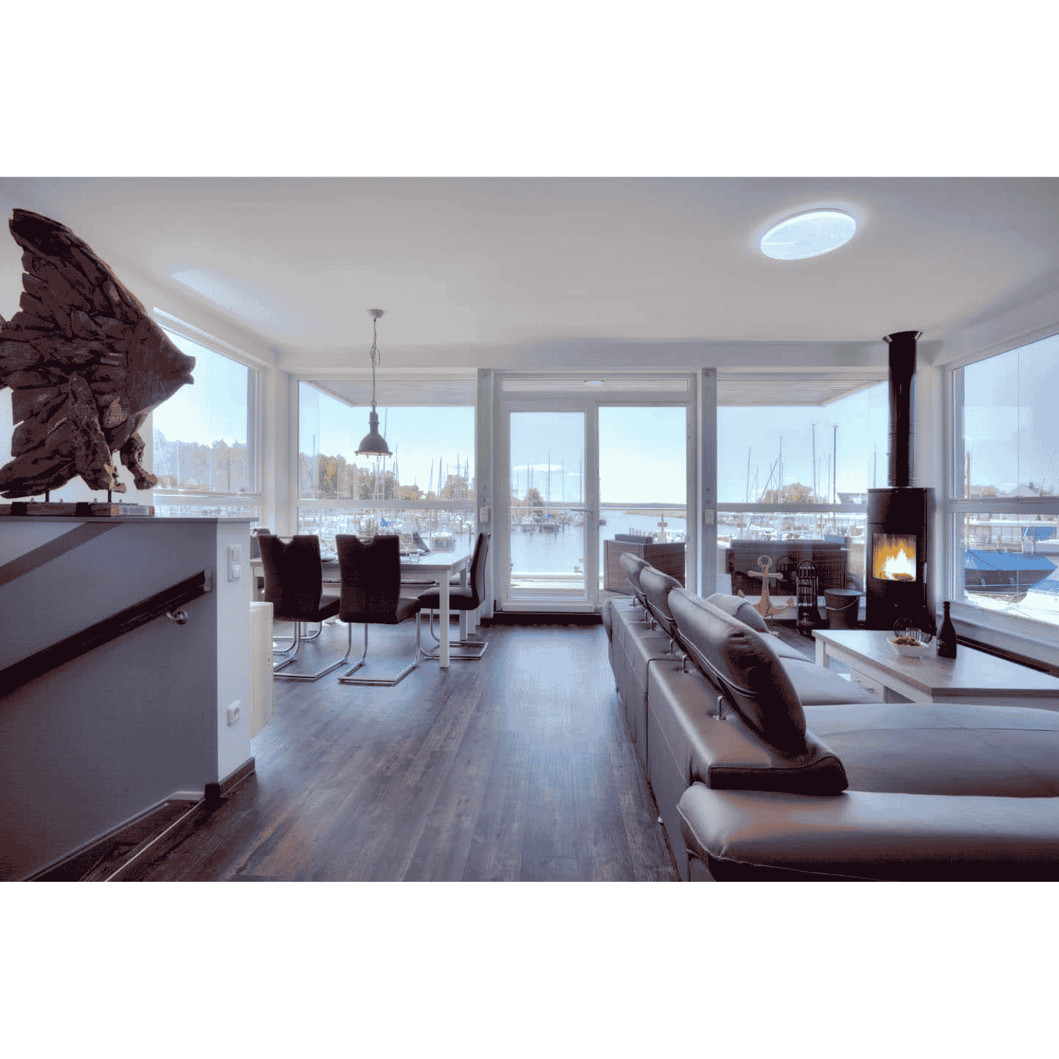 Modernes Wohnzimmer im Floating House Peenemünde mit Ledersofa, Kamin und Panoramablick auf den Yachthafen auf Usedom