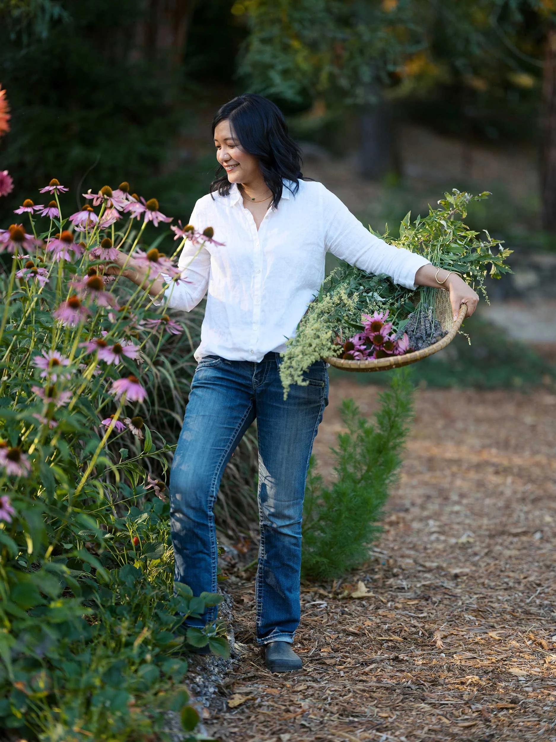 Woman walking through a garden and touching flowers representing intuitive healing and connection with nature.