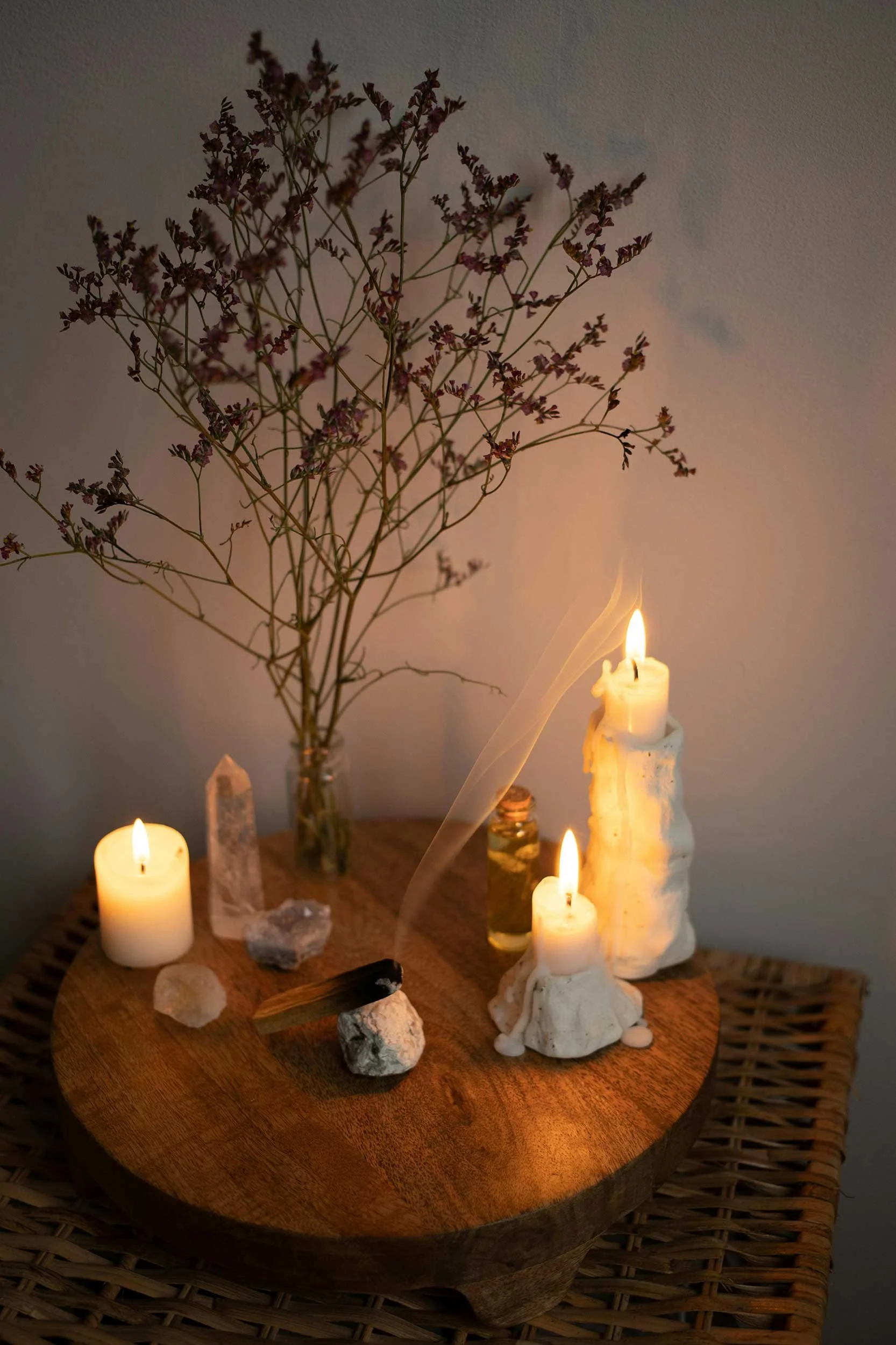 Small altar with candles, crystals, and dried plants used for energy healing and spiritual practice.