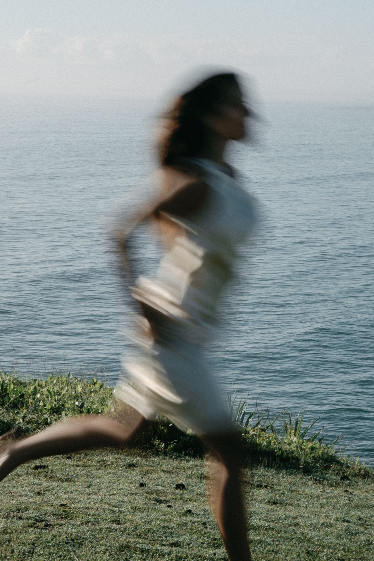 Woman moving freely along the shoreline representing intuitive healing and connection with nature.