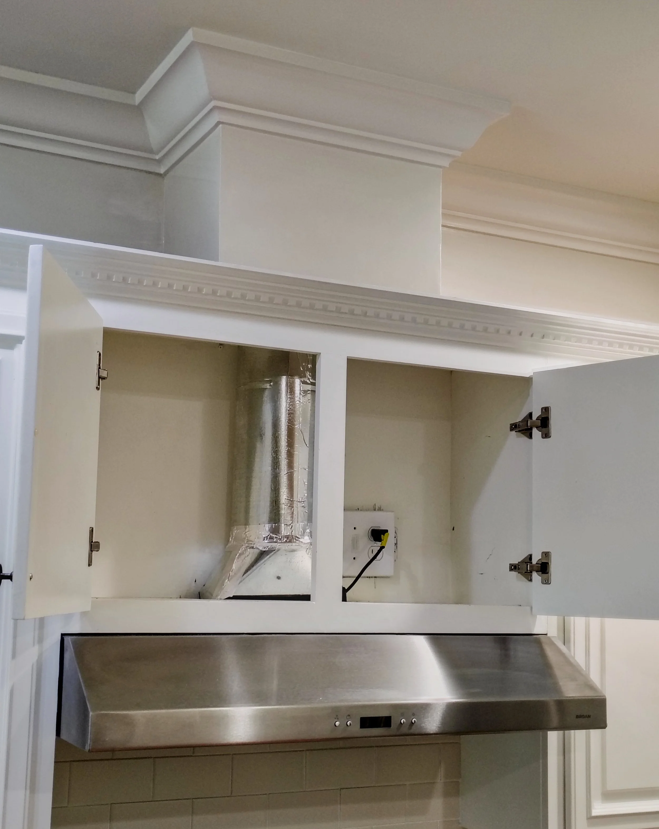 Newly installed kitchen hood vent and finished drywall and trim chase