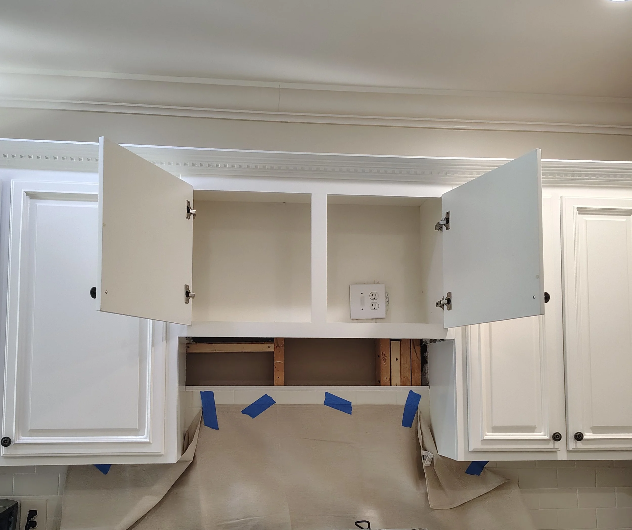 Kitchen upper cabinets with some doors open, showing empty interior space. The cabinet includes an electrical outlet inside.