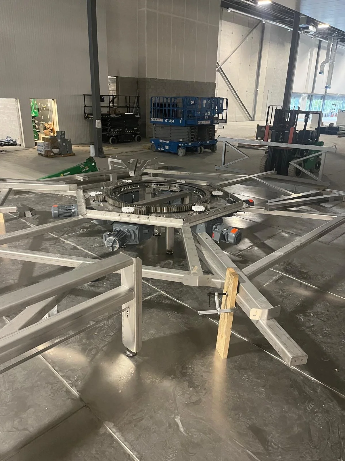 Industrial millwright site with metal framework, lift equipment, and construction tools and materials in a warehouse or factory.