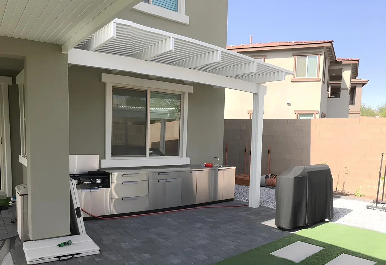 Backyard patio with outdoor kitchen, covered area, grill, and artificial grass
