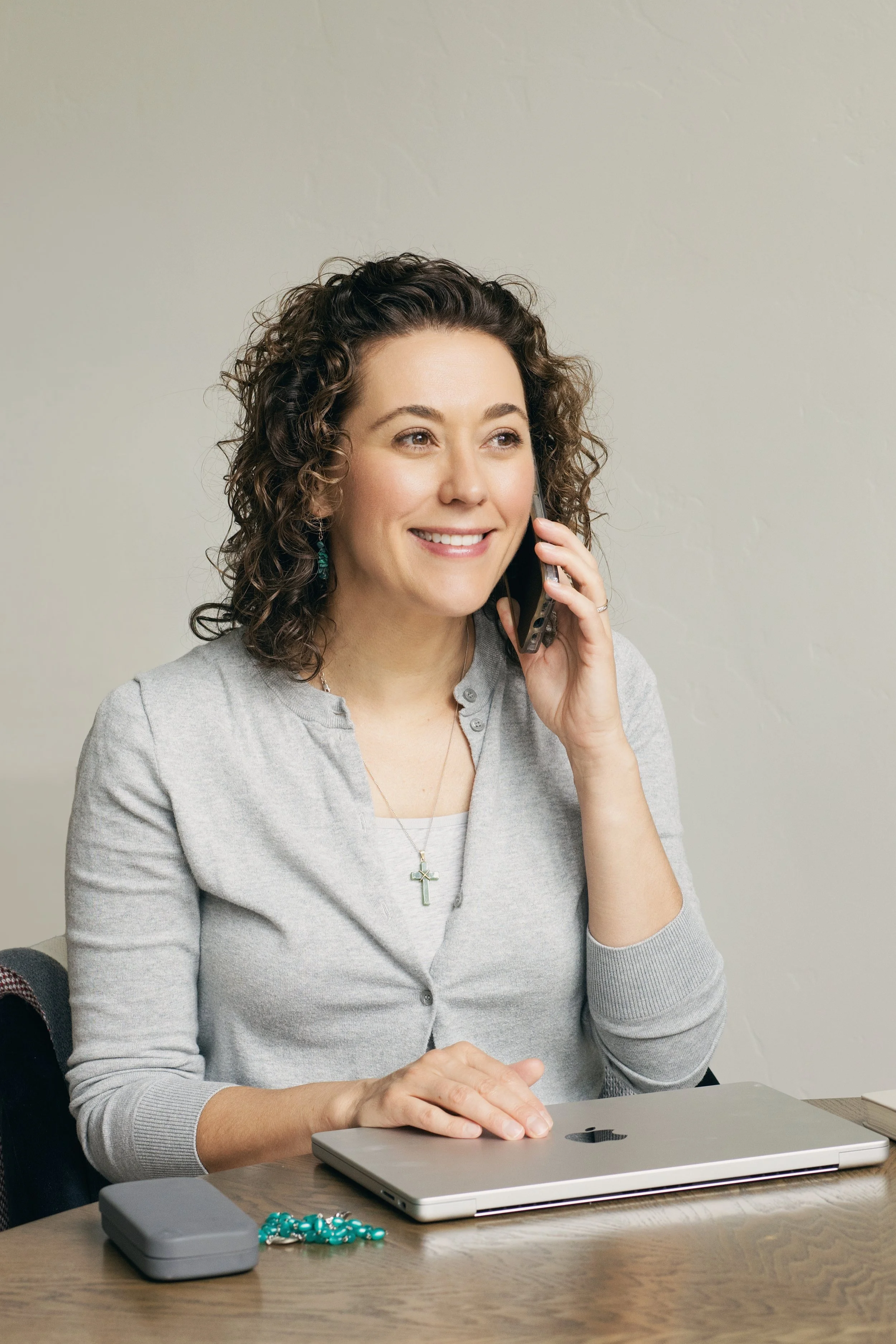 Curly haired women on the phone in phone in front of a computer