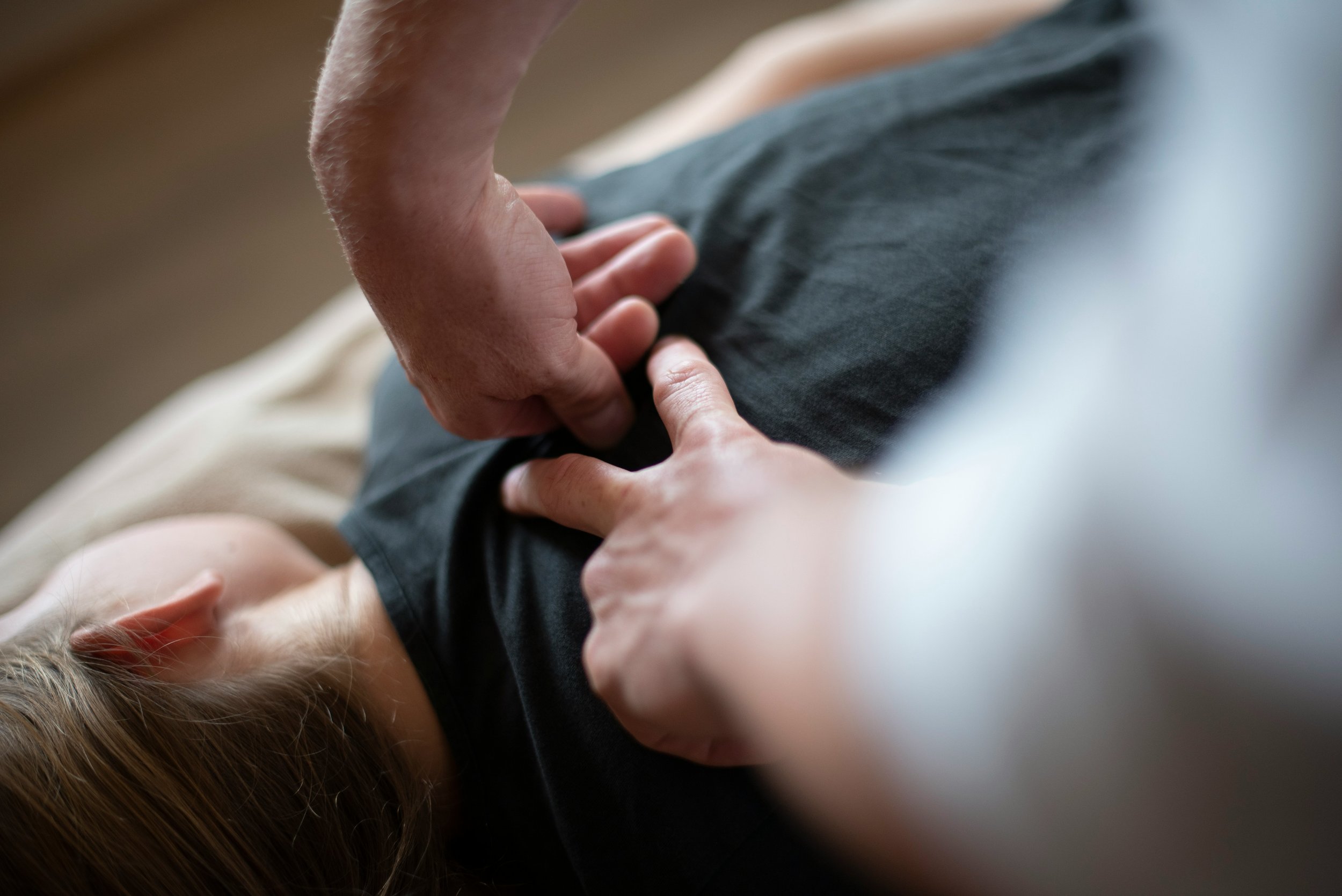 A person chiropractic treatment on a woman lying on the ground.