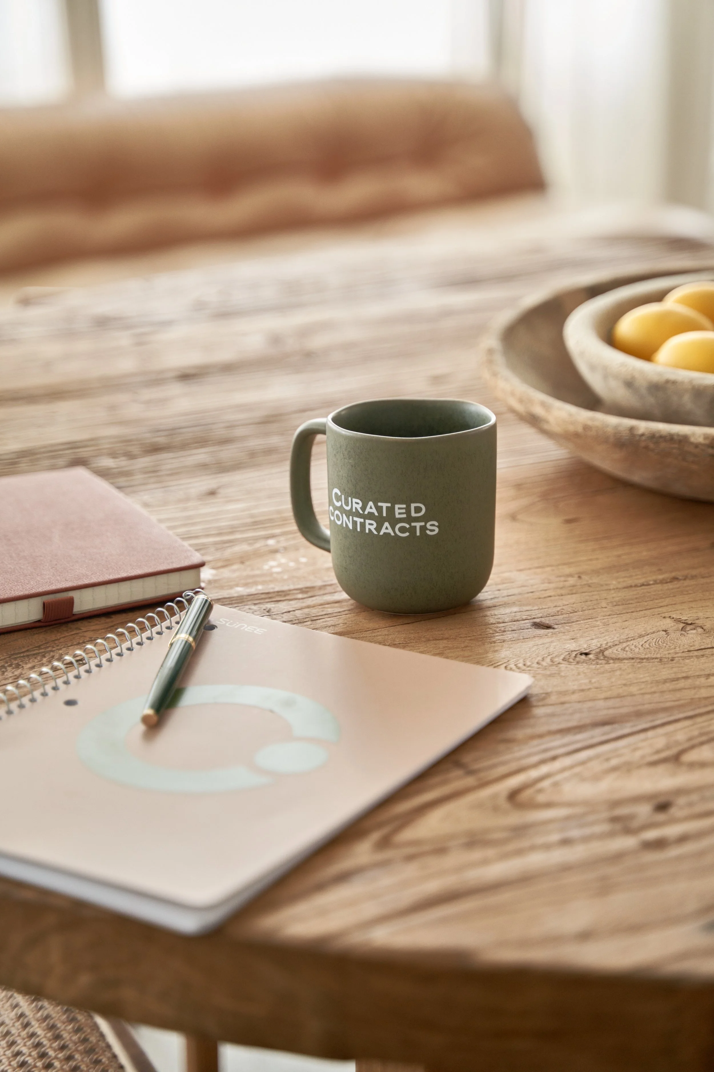 Curated Contracts mug and workspace with notebook and pen representing lawyer drafted contract templates for freelancers and creative professionals.