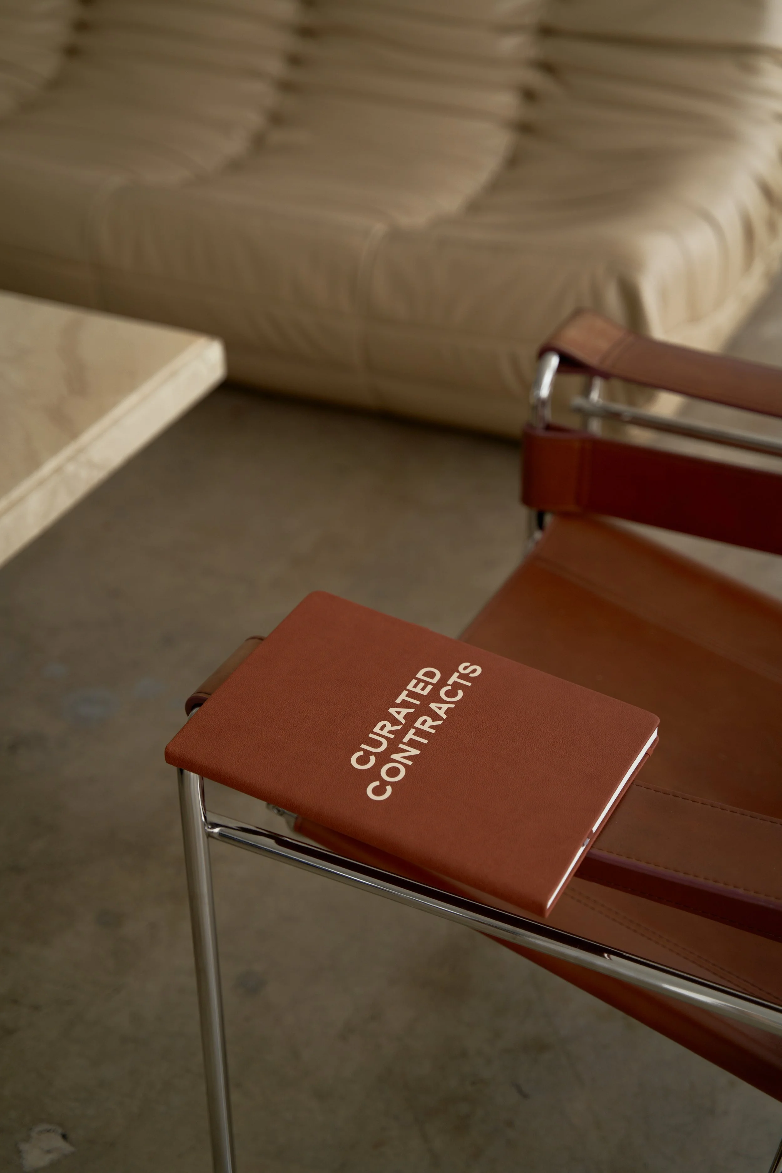 Curated Contracts branded notebook on a chair, representing lawyer drafted contract templates for creative professionals and small businesses.