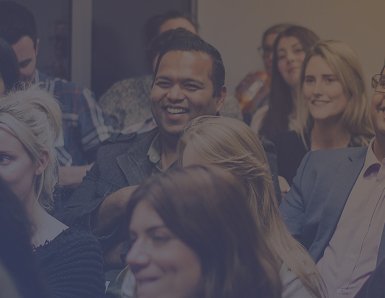 People sitting in a conference or event, smiling and engaging.