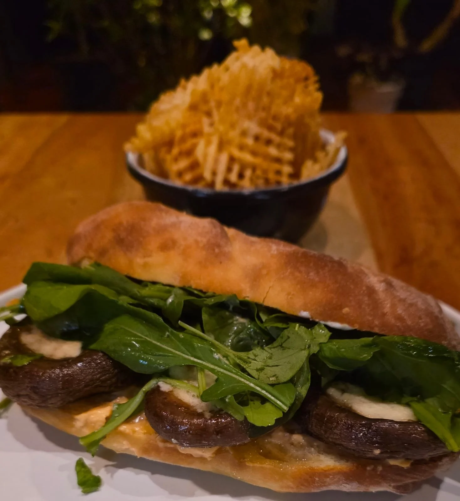 Sándwich de hongos portobellos rellenos en pan artesanal, acompañado de papas fritas
