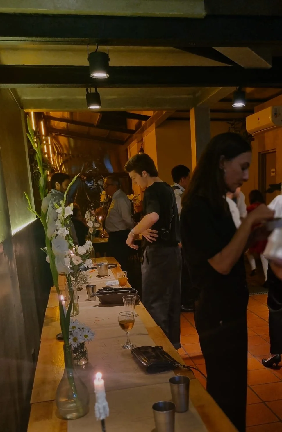 Personas sirviendo comida en un restaurante con decoraciones florales y velas.