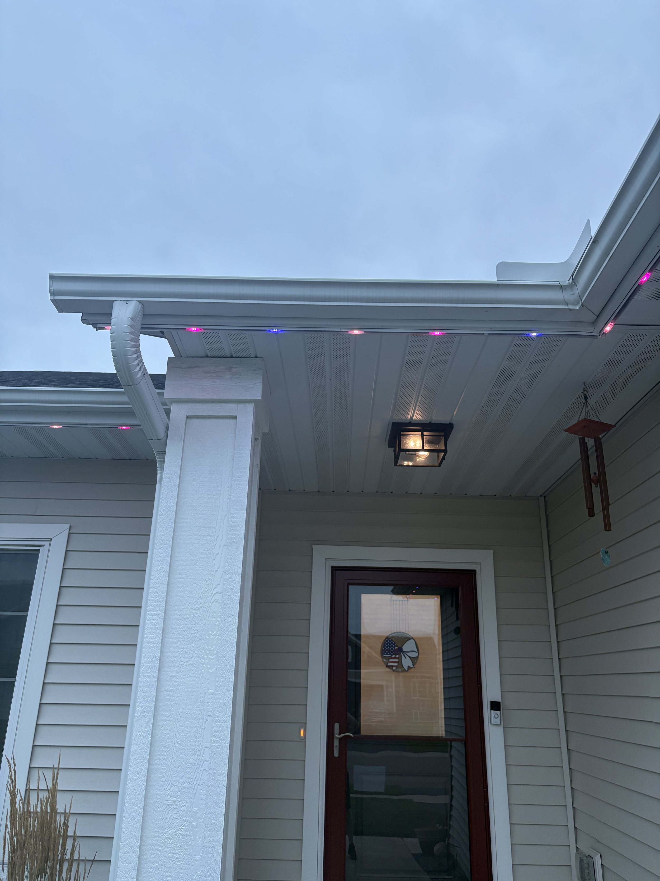 front door of a tan home looking up at the lights on the roof line