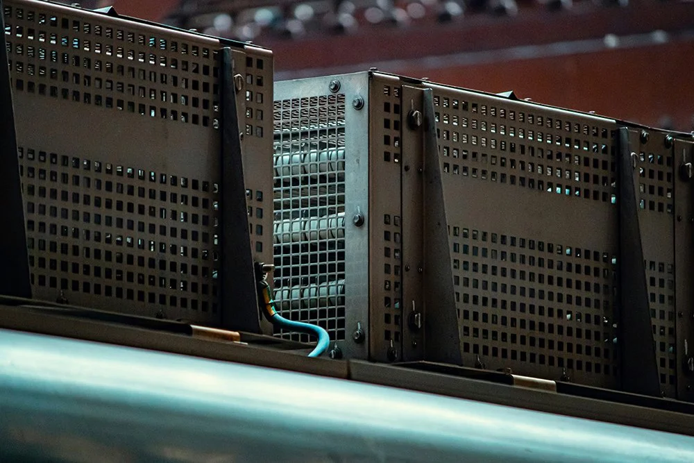 Componentes electrónicos metálicos con rejillas y cables en un entorno industrial o de maquinaria.