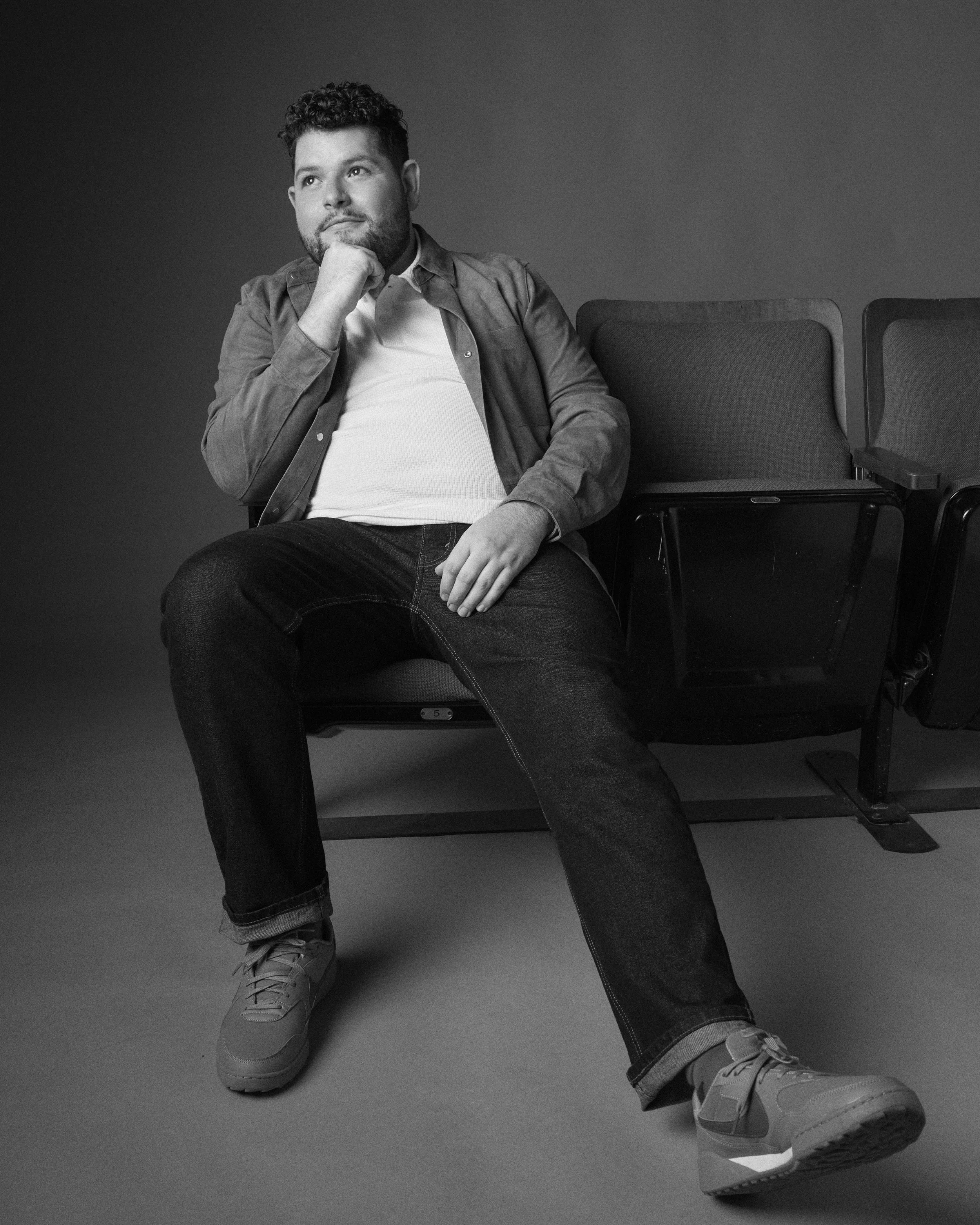 Actor, director, and writer Nicholas Molencupp sitting thoughtfully in a theater seat in a black and white portrait
