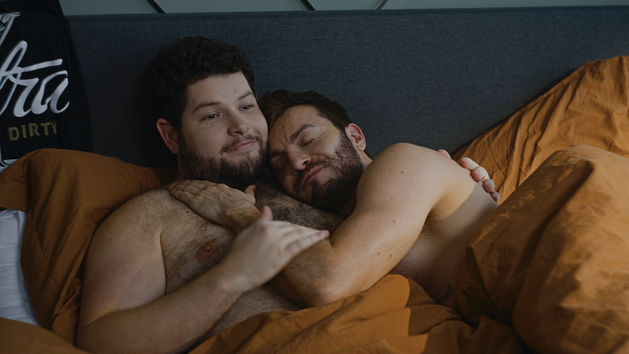 Actors Nicholas Molencupp and Cameron Moir sharing an intimate moment in bed as Nick and Beau in the film In Between