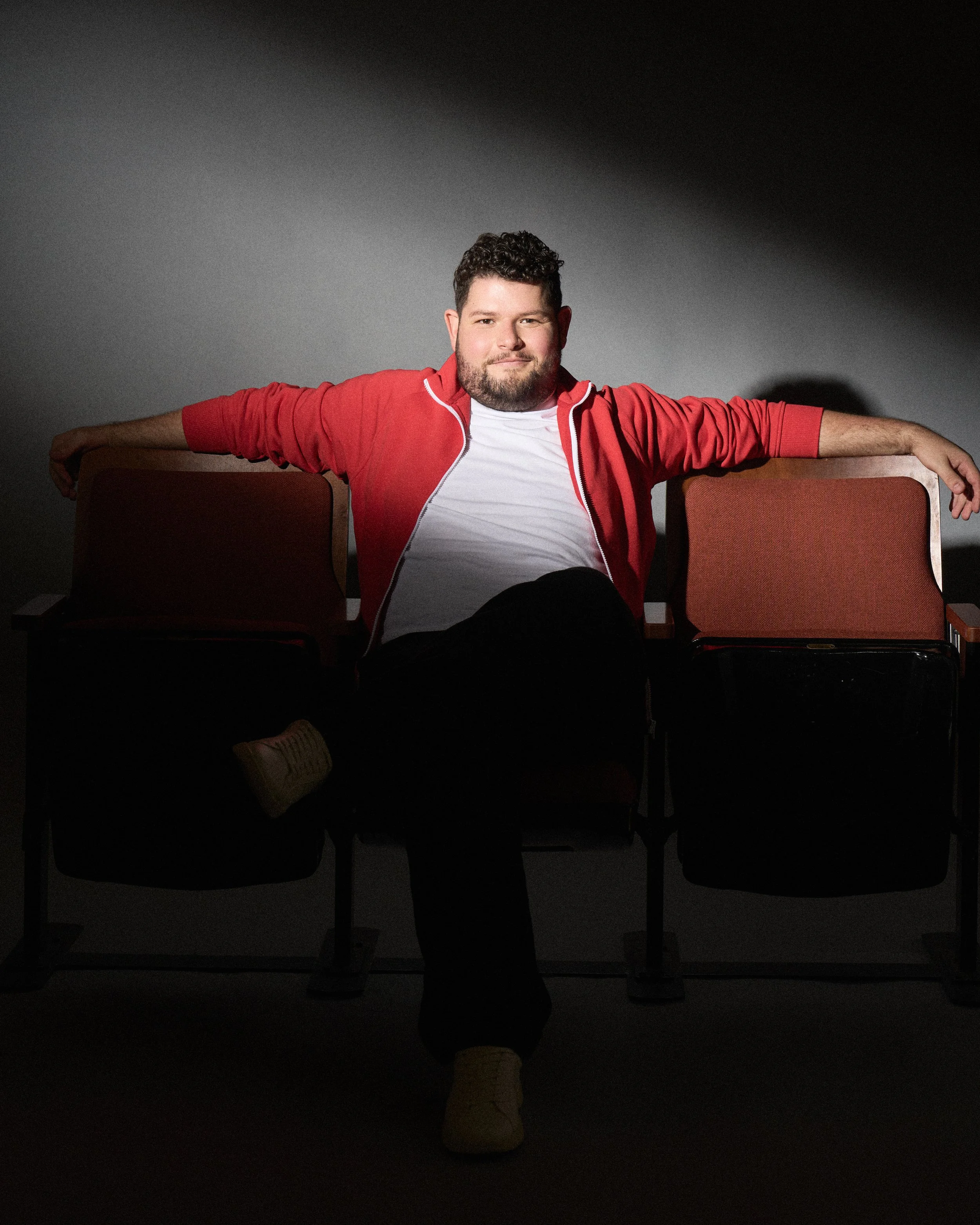 Director and filmmaker Nicholas Molencupp sitting confidently in theater seats under a spotlight