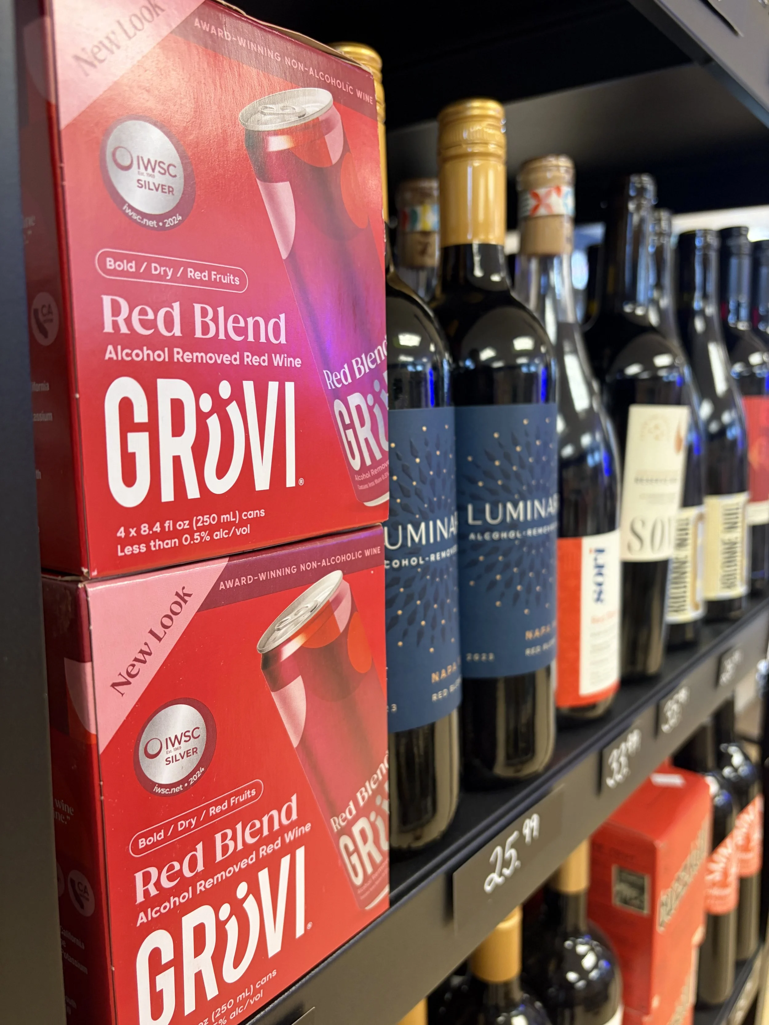 Boxes of Grivi alcohol-free red wine blend on store shelf with various N/A wine bottles behind.