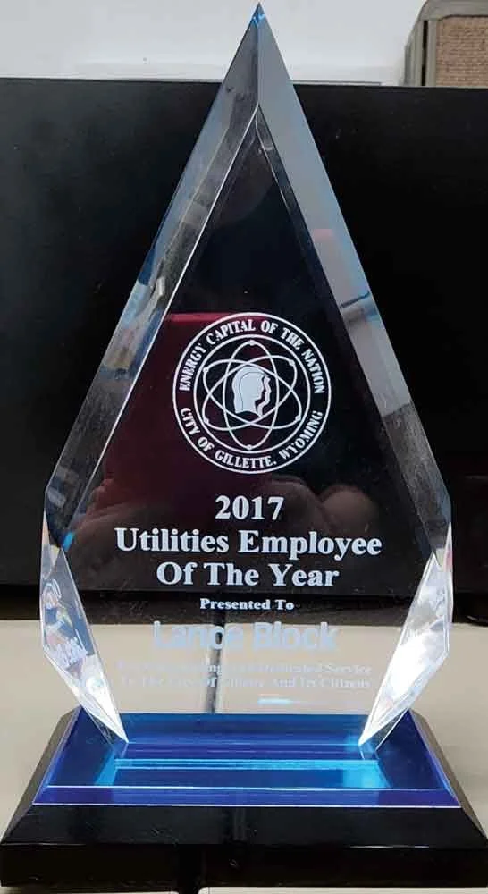 A clear, diamond-shaped glass award on a black and blue base, with an engraved seal of Gillette, Utah, and text indicating it is for the 2017 Utilities Employee of the Year, presented to Ling Block.