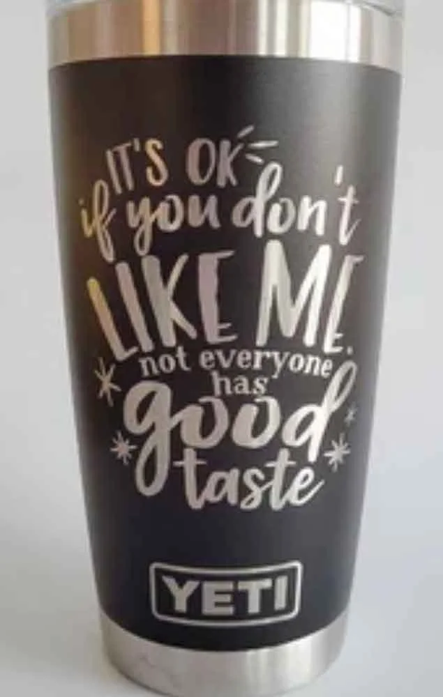 A black YETI tumbler with white and yellow text that reads, "It's OK if you don't LIKE ME, not everyone has good taste."