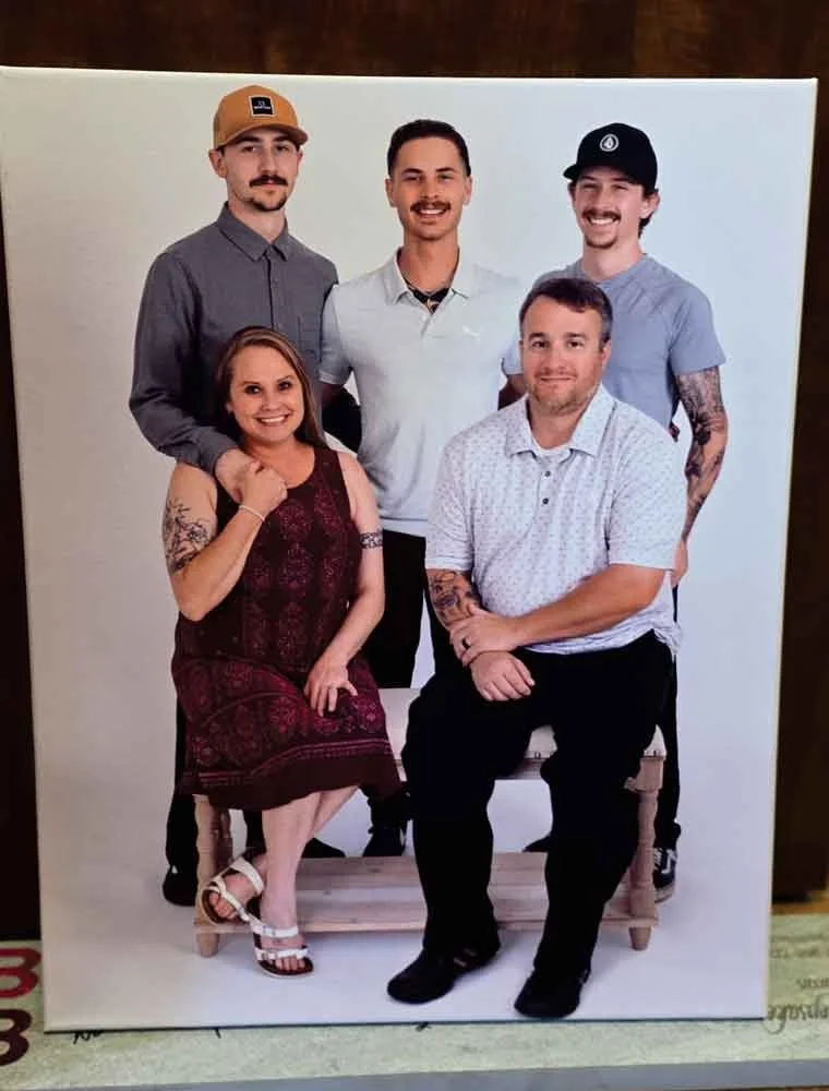 A group photo of five people, three men standing in the back and one man and one woman sitting in front, on a white background.