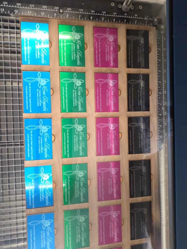 Colorful business cards with a bee logo and the text 'High Hopes' in a wooden display box. The cards are blue, green, pink, and black.