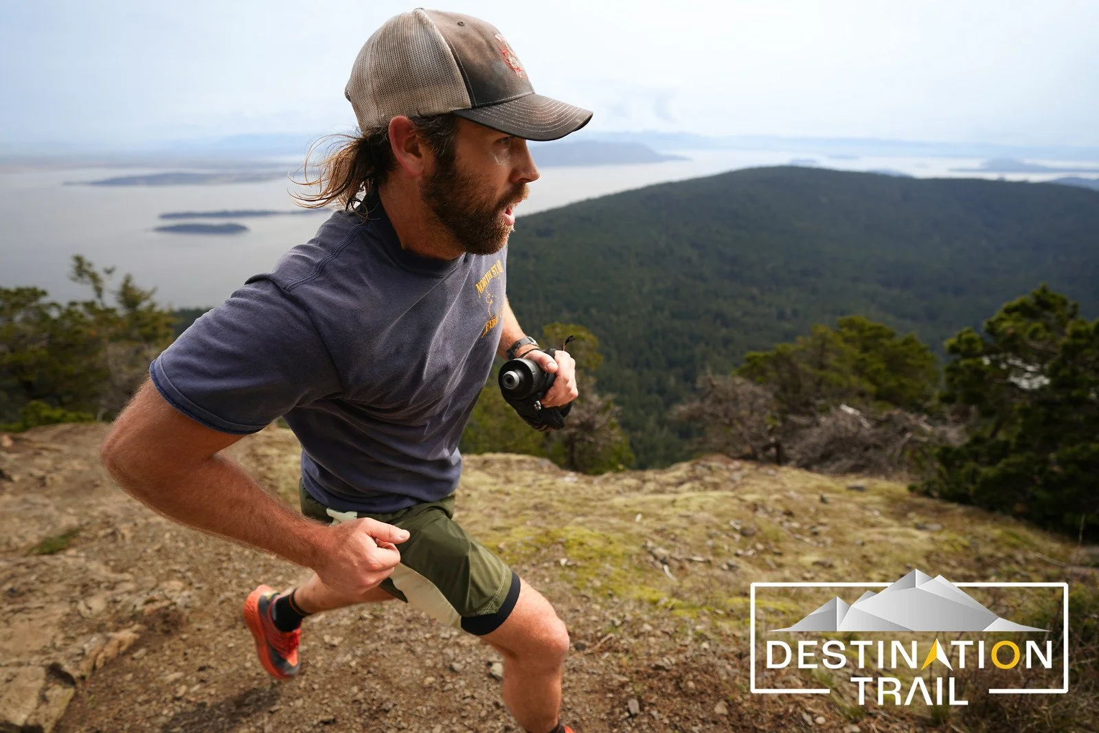 A closeup of a male runner on the trails at Orcas Island with the ocean and islands behind him