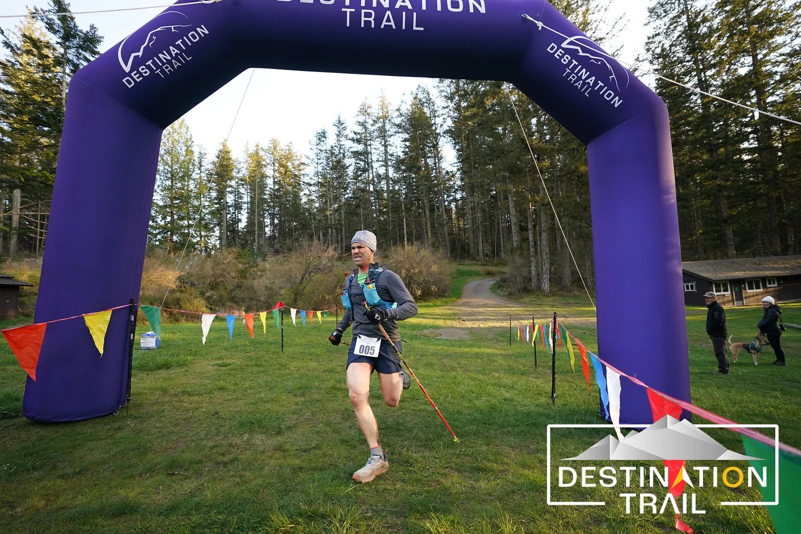 A runner finishes a trail race on Orcas Island underneath the blue finisher arch