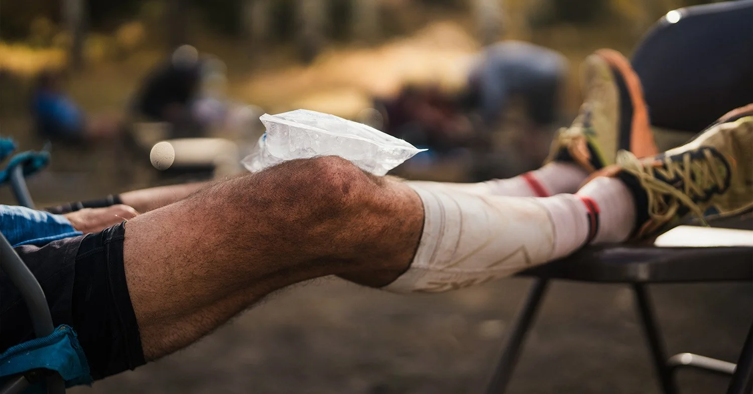 A man ices his knee at an aid station during an ultramarathon