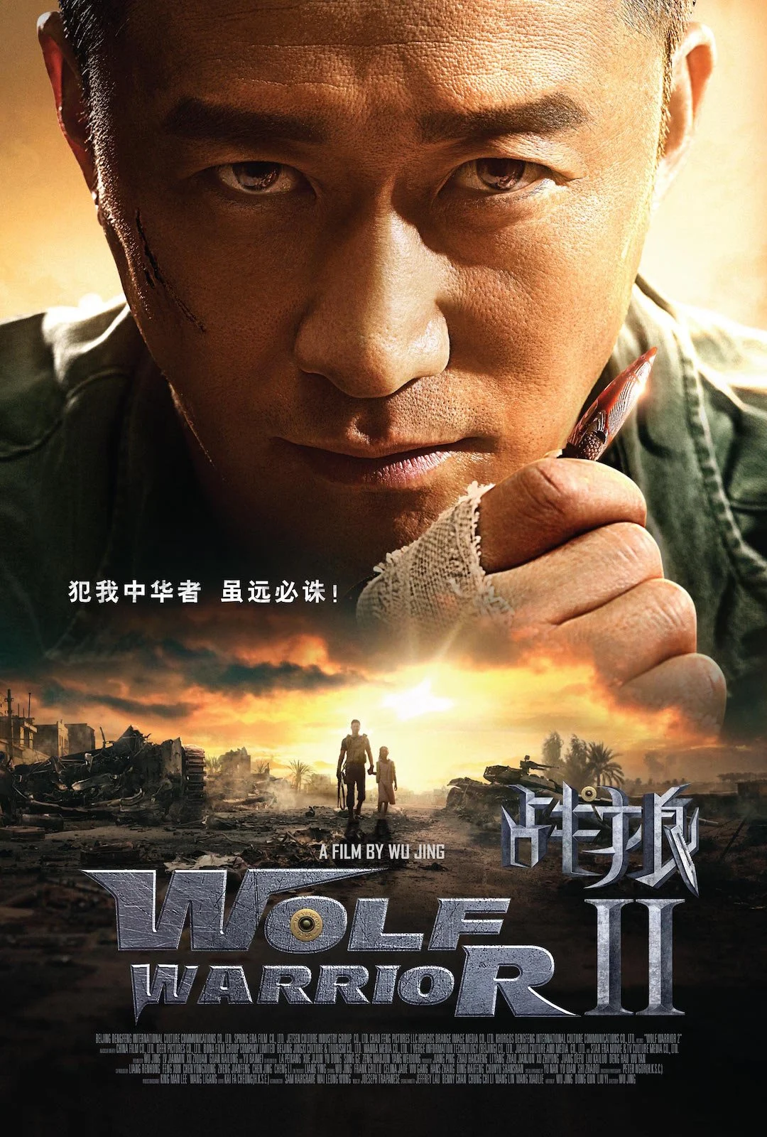 Close-up of a man with a serious expression holding a feather pen near his chin, with a landscape of destroyed buildings and two figures walking away in the background. Text in Chinese and English reads 'Wolf Warrior II' and 'A film by Wu Jing'.