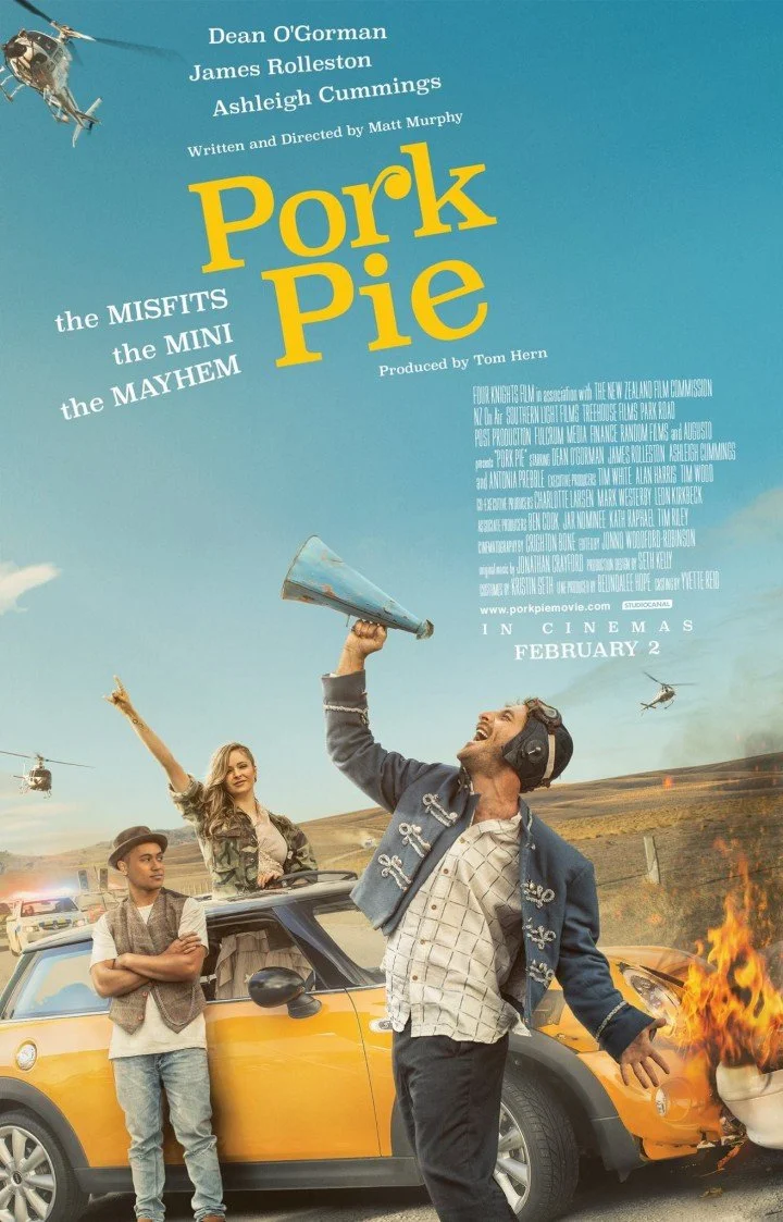 A promotional poster for the movie 'Pork Pie' featuring three characters in front of a yellow car, with a fire on the front of the car and helicopters in the sky.
