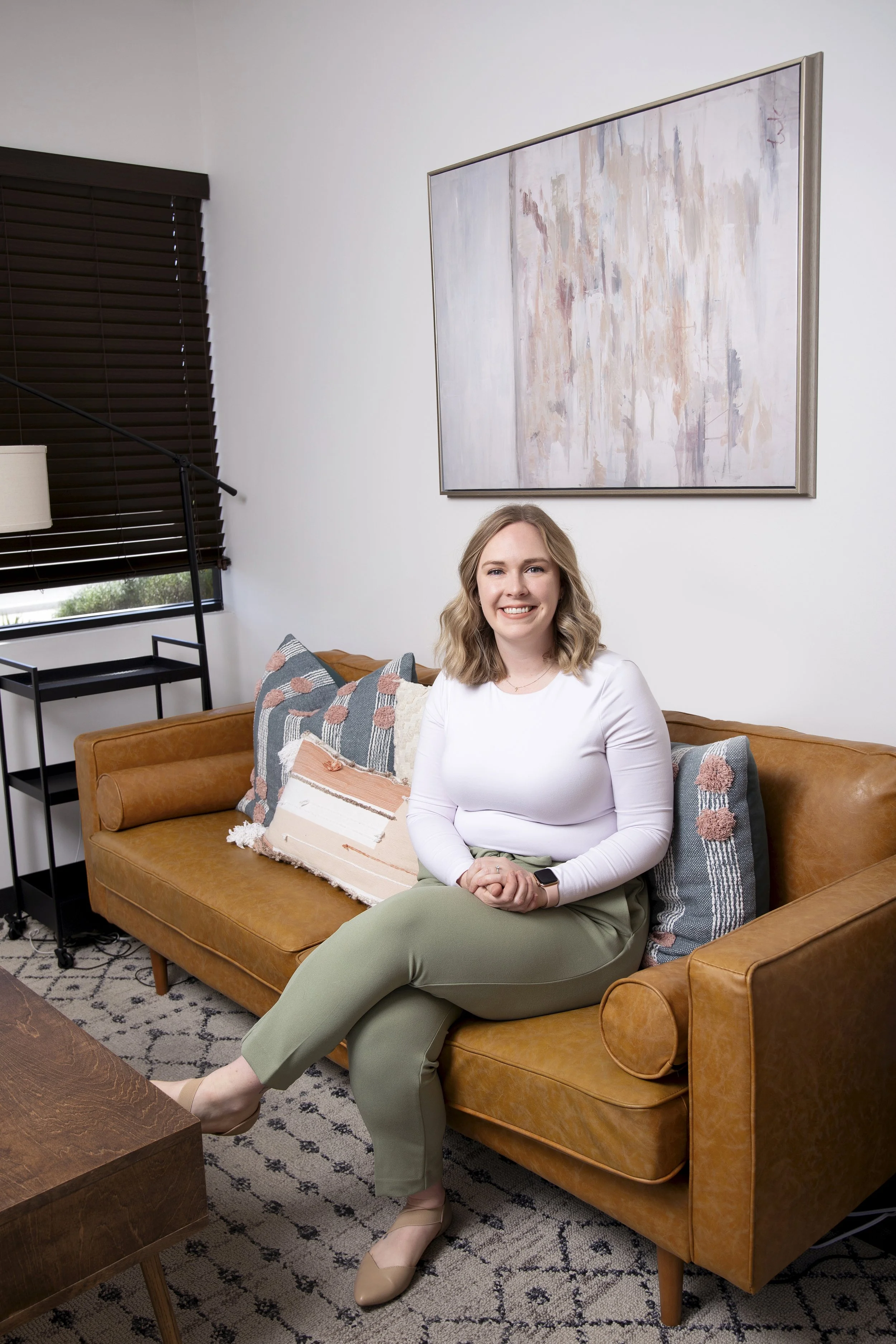 Young woman smiling with medium-length blonde hair sitting in therapy office in Mesa, Arizona.