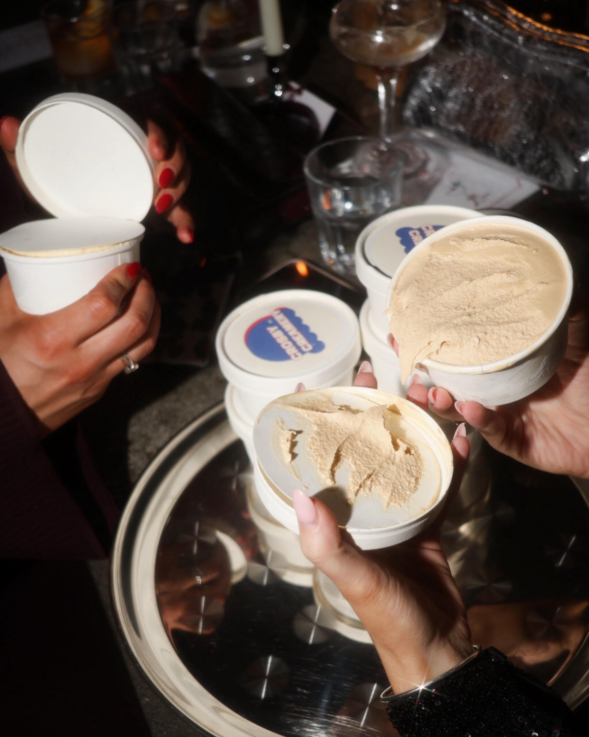 People holding open containers of vanilla ice cream in a social setting.